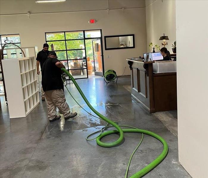 technicians cleaning water off of an office building floor