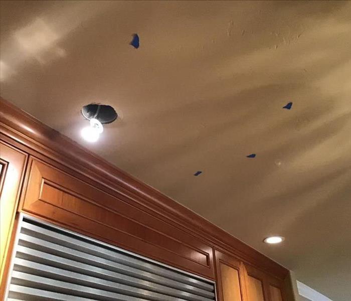 hole in ceiling where light fixture is located, blue tape on the wall in several places