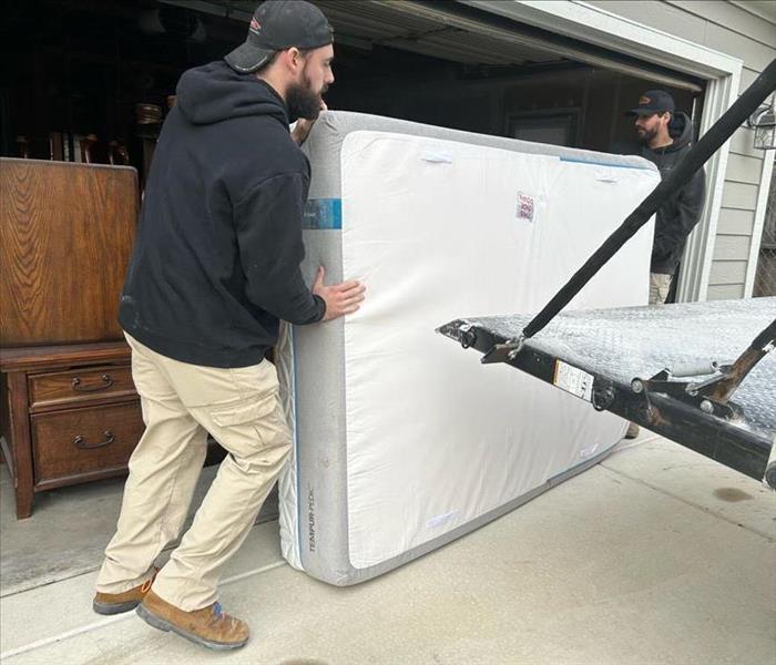 men lifting mattress into car