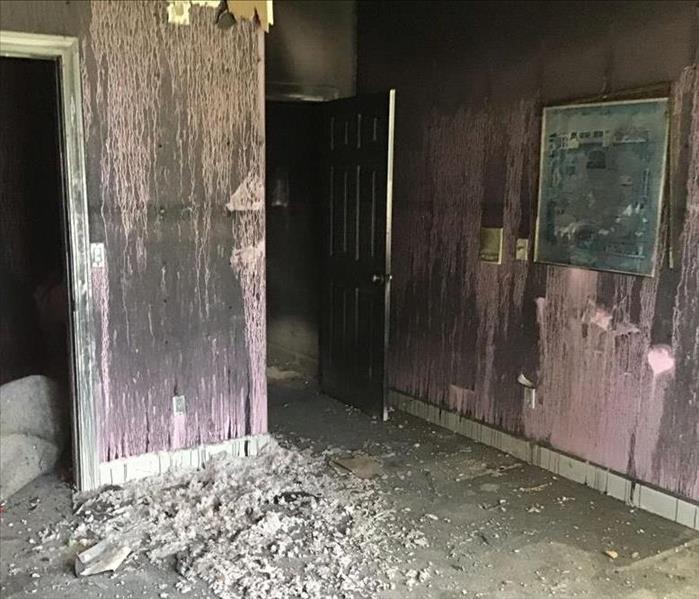 pink walls with soot and debris, charred portrait on the right near doorway