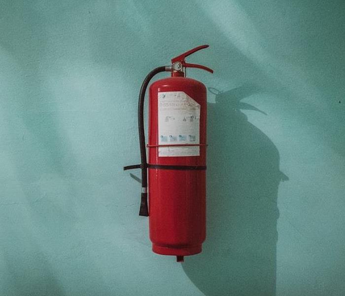 Fire extinguisher hung on a teal wall