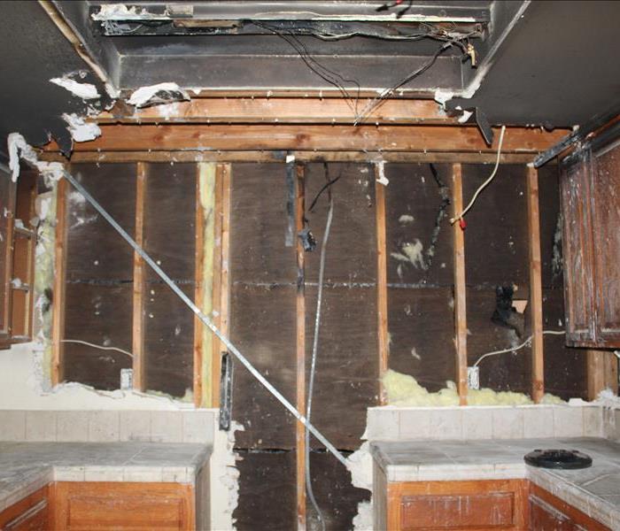 burned kitchen cabinet, ceiling, and countertop. Drywall charred and removed, green equipment