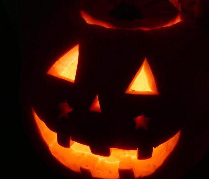 pumpkin glowing in the dark with triangle eyes and nose and a smile
